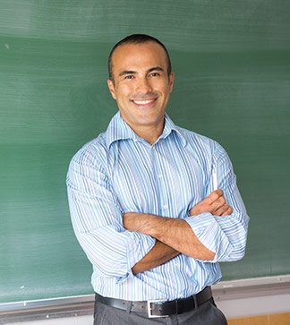 Teacher poses in front of a blackboard